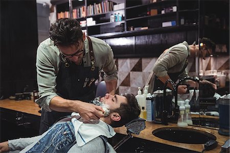 simsearch:6109-08928845,k - Barber applying cream on clients beard in baber shop Fotografie stock - Premium Royalty-Free, Codice: 6109-08928730