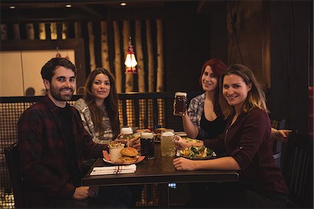 Portrait of happy friends enjoying food together in bar Stock Photo - Premium Royalty-Free, Code: 6109-08928869