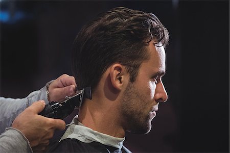 Man getting his hair trimmed with trimmer in barber shop Foto de stock - Royalty Free Premium, Número: 6109-08928812