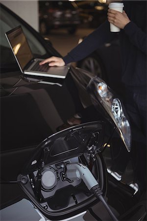 ricaricare (oggetti) - Man using laptop while charging electric car in garage Fotografie stock - Premium Royalty-Free, Codice: 6109-08928995