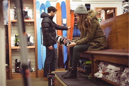 Woman trying on ski boot while man selecting ski in a shop Photographie de stock - Premium Libres de Droits, Code: 6109-08928916
