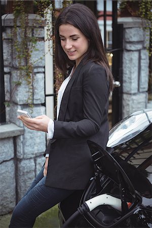 simsearch:6109-08929005,k - Beautiful woman using mobile phone while charging electric car at vehicle charging station Stock Photo - Premium Royalty-Free, Code: 6109-08929052