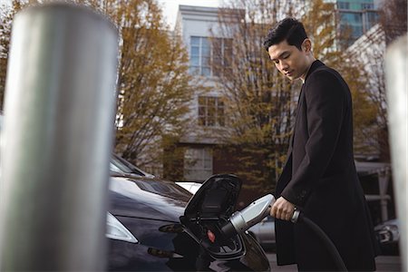 electricidad - Confident man charging electric car at electric vehicle charging station Foto de stock - Sin royalties Premium, Código: 6109-08929072