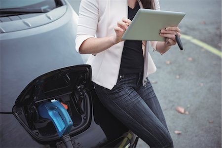 simsearch:6109-08928992,k - Mid section of woman using digital tablet while charging electric car on street Stock Photo - Premium Royalty-Free, Code: 6109-08929020