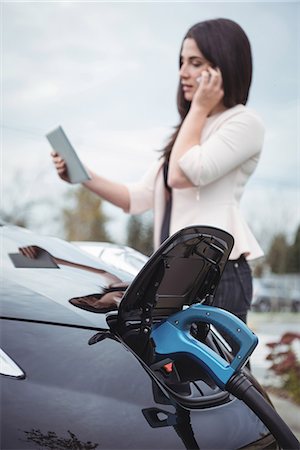 power outlet - Beautiful woman talking on mobile phone while charging electric car on street Foto de stock - Sin royalties Premium, Código: 6109-08929033