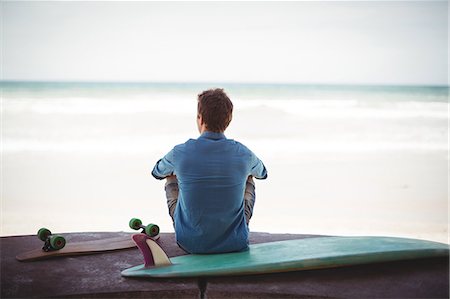 simsearch:649-07437735,k - Rear view of man with skateboard and surfboard sitting on beach Photographie de stock - Premium Libres de Droits, Code: 6109-08929140