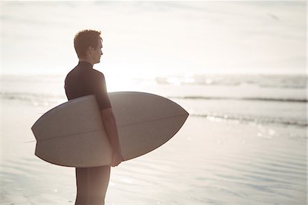 simsearch:649-07437735,k - Thoughtful surfer standing with surfboard on beach Photographie de stock - Premium Libres de Droits, Code: 6109-08929150