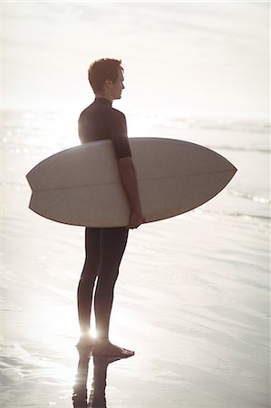 simsearch:649-07437735,k - Thoughtful surfer standing with surfboard on beach Photographie de stock - Premium Libres de Droits, Code: 6109-08929151