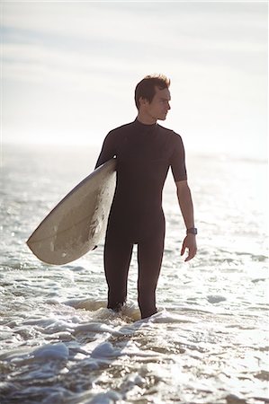 simsearch:649-07437735,k - Thoughtful surfer standing with surfboard in sea Photographie de stock - Premium Libres de Droits, Code: 6109-08929155