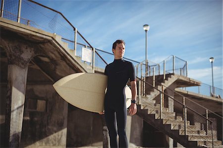 surfer standing - Thoughtful surfer standing with surfboard on beach Stock Photo - Premium Royalty-Free, Code: 6109-08929163