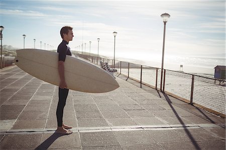 Thoughtful surfer standing with surfboard on pier at beach Foto de stock - Sin royalties Premium, Código: 6109-08929167