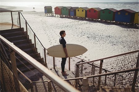 Thoughtful surfer standing with surfboard on beach Stock Photo - Premium Royalty-Free, Code: 6109-08929166