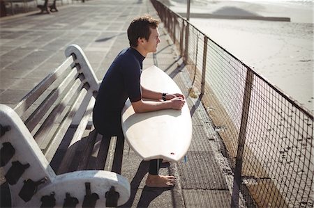 simsearch:649-07437735,k - Thoughtful surfer sitting with surfboard on pier at beach Photographie de stock - Premium Libres de Droits, Code: 6109-08929169