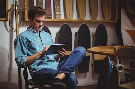 Man using digital tablet in surfboard shop Stock Photo - Premium Royalty-Free, Code: 6109-08929194