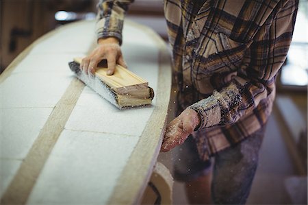 process business - Mid-section of man using sanding block in the surfboard workshop Stock Photo - Premium Royalty-Free, Code: 6109-08929112