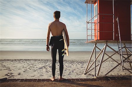 simsearch:649-07437735,k - Rear view of surfer standing with surfboard on beach Photographie de stock - Premium Libres de Droits, Code: 6109-08929115