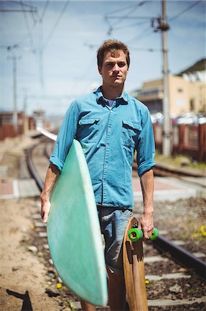 simsearch:6109-08929136,k - Portrait of man carrying skateboard and surfboard crossing railway track Stockbilder - Premium RF Lizenzfrei, Bildnummer: 6109-08929138