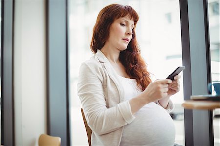 simsearch:6109-08944310,k - Pregnant businesswoman using mobile phone in office cafeteria Photographie de stock - Premium Libres de Droits, Code: 6109-08929290