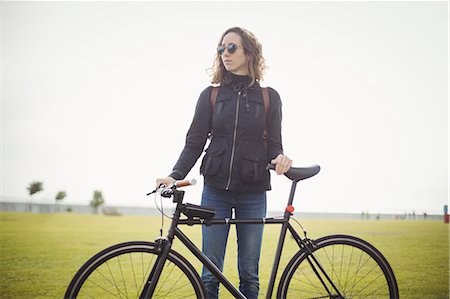 simsearch:614-02679479,k - Woman with sunglasses holding bicycle in the park Foto de stock - Sin royalties Premium, Código: 6109-08929227