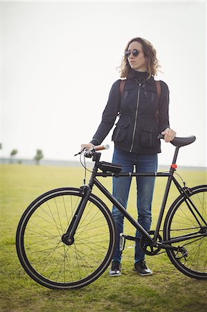 simsearch:614-02679479,k - Woman with sunglasses holding bicycle in the park Foto de stock - Sin royalties Premium, Código: 6109-08929228