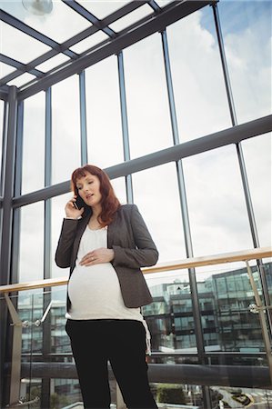 simsearch:6102-08996340,k - Pregnant businesswoman talking on mobile phone near corridor in office Stockbilder - Premium RF Lizenzfrei, Bildnummer: 6109-08929344