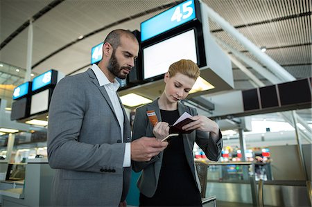 simsearch:6109-08802775,k - Business people holding boarding pass and using mobile phone in airport terminal Photographie de stock - Premium Libres de Droits, Code: 6109-08929367