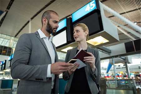 simsearch:6109-08802694,k - Business people holding boarding pass and using mobile phone in airport terminal Stock Photo - Premium Royalty-Free, Code: 6109-08929368