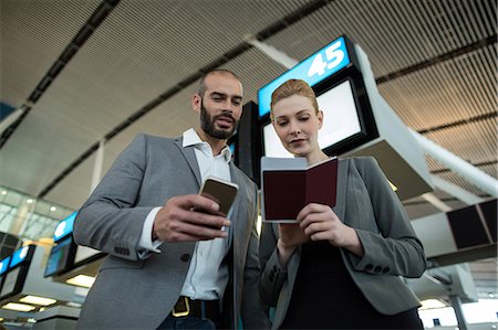 simsearch:6109-08802775,k - Business people holding boarding pass and using mobile phone in airport terminal Photographie de stock - Premium Libres de Droits, Code: 6109-08929370