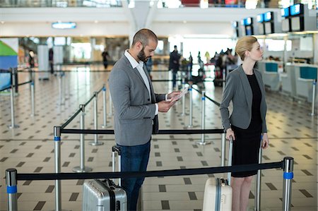 simsearch:6111-06727323,k - Businesspeople waiting in queue at a check-in counter with luggage in airport terminal Stock Photo - Premium Royalty-Free, Code: 6109-08929377