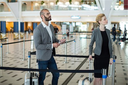 simsearch:6111-06727323,k - Businesspeople waiting in queue at the check-in counter with luggage in airport terminal Stock Photo - Premium Royalty-Free, Code: 6109-08929378