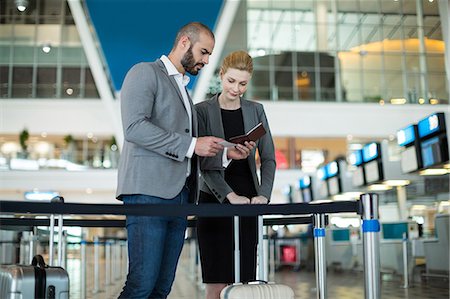 simsearch:6109-08929360,k - Businesspeople checking their passport at check-in counter in airport terminal Photographie de stock - Premium Libres de Droits, Code: 6109-08929379