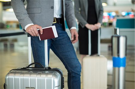 simsearch:6111-06727323,k - Businesspeople waiting in queue at a check-in counter with luggage in airport terminal Stock Photo - Premium Royalty-Free, Code: 6109-08929384