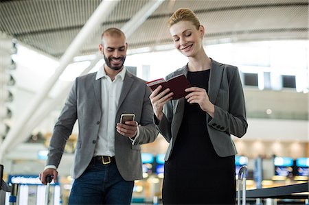 simsearch:6111-06727323,k - Businesspeople waiting in queue at a check-in counter with luggage in airport terminal Stock Photo - Premium Royalty-Free, Code: 6109-08929392