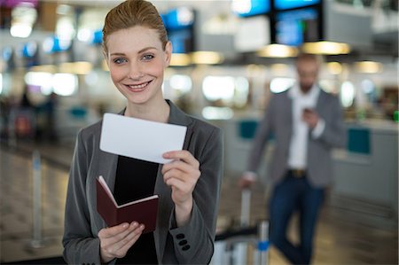 registro - Portrait of smiling businesswoman showing her boarding pass at airport terminal Foto de stock - Sin royalties Premium, Código: 6109-08929396