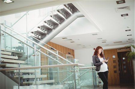 simsearch:6109-08953148,k - Pregnant businesswoman using mobile phone near staircase in office Stock Photo - Premium Royalty-Free, Code: 6109-08929336