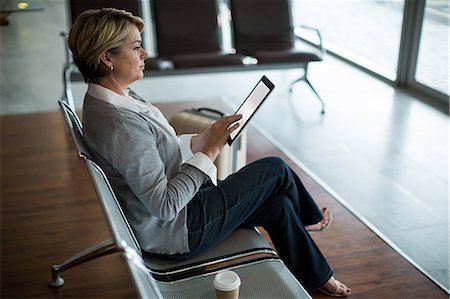 simsearch:6109-08929459,k - Businesswoman using digital tablet in waiting area at airport terminal Foto de stock - Royalty Free Premium, Número: 6109-08929446