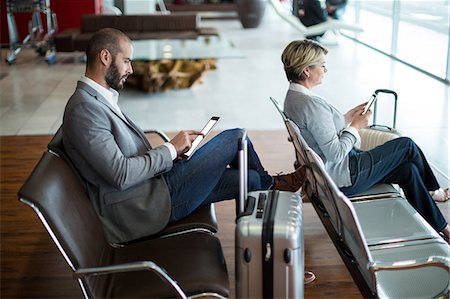 simsearch:6109-08802775,k - Businesspeople using digital tablet and mobile phone in waiting area at airport terminal Photographie de stock - Premium Libres de Droits, Code: 6109-08929448