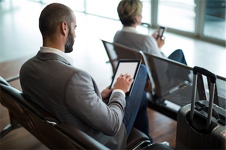 simsearch:6109-08929459,k - Businessman using digital tablet in waiting area at airport terminal Foto de stock - Royalty Free Premium, Número: 6109-08929449