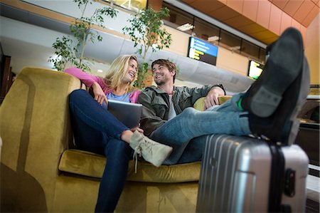 passenger at airport - Smiling couple interacting with each other in waiting area at airport terminal Stock Photo - Premium Royalty-Free, Code: 6109-08929483
