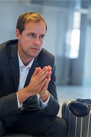 simsearch:6109-08929459,k - Tense businessman sitting in waiting area with luggage at airport terminal Foto de stock - Royalty Free Premium, Número: 6109-08929487