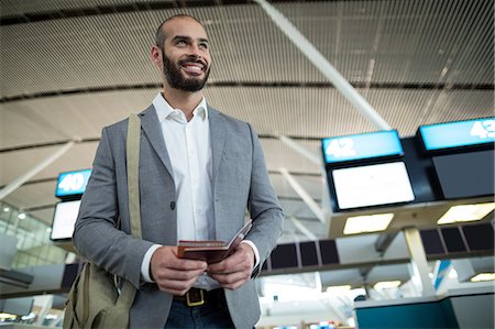 simsearch:400-03913175,k - Smiling businessman holding a boarding pass and passport at airport terminal Foto de stock - Royalty Free Premium, Número: 6109-08929403