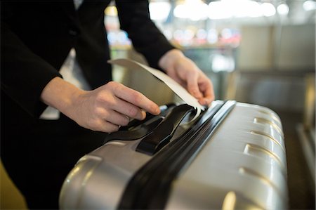 simsearch:6109-08929425,k - Airline check-in attendant sticking tag to the luggage of commuter at airport Foto de stock - Sin royalties Premium, Código: 6109-08929420