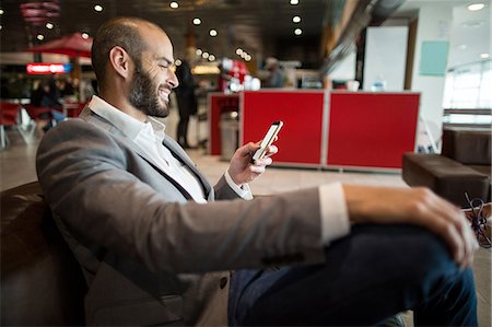 simsearch:6111-06727323,k - Businessman using mobile phone in waiting area at airport terminal Stock Photo - Premium Royalty-Free, Code: 6109-08929427