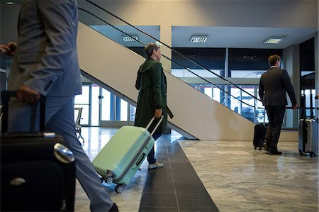 simsearch:614-06115991,k - Businesspeople walking with luggage in waiting area at airport Foto de stock - Royalty Free Premium, Número: 6109-08929543