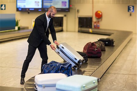 Businessman picking his luggage from baggage claim area at airport Stockbilder - Premium RF Lizenzfrei, Bildnummer: 6109-08929544