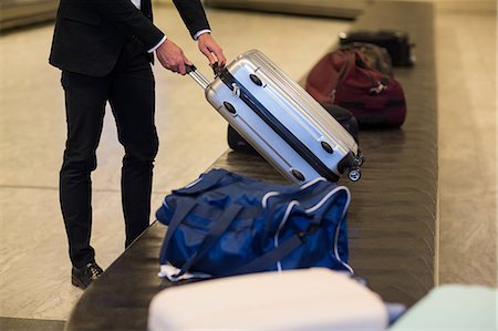 simsearch:400-08492073,k - Businessman picking his luggage from baggage claim area at airport Photographie de stock - Premium Libres de Droits, Code: 6109-08929553