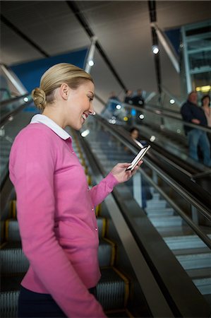 simsearch:632-01156525,k - Female commuter using mobile phone on escalator in airport Photographie de stock - Premium Libres de Droits, Code: 6109-08929564