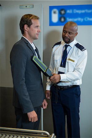 Airport security officer using a hand held metal detector to check a commuter in airport Photographie de stock - Premium Libres de Droits, Code: 6109-08929526