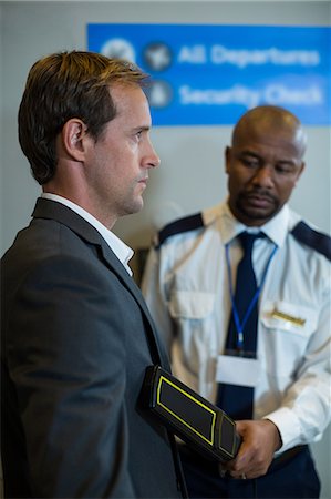 simsearch:6109-08722615,k - Airport security officer using a hand held metal detector to check a commuter in airport Stock Photo - Premium Royalty-Free, Code: 6109-08929528