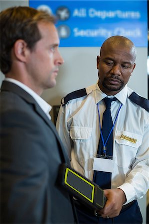 simsearch:6109-08722675,k - Airport security officer using a hand held metal detector to check a commuter in airport Fotografie stock - Premium Royalty-Free, Codice: 6109-08929529